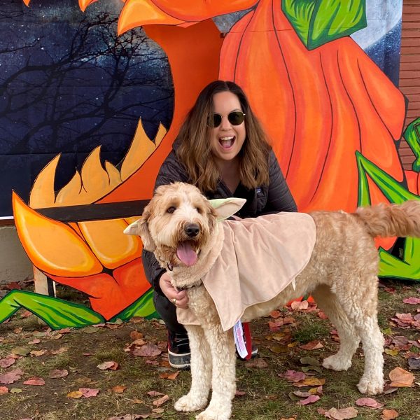 A doodle dressed as Yoda poses with his handler.