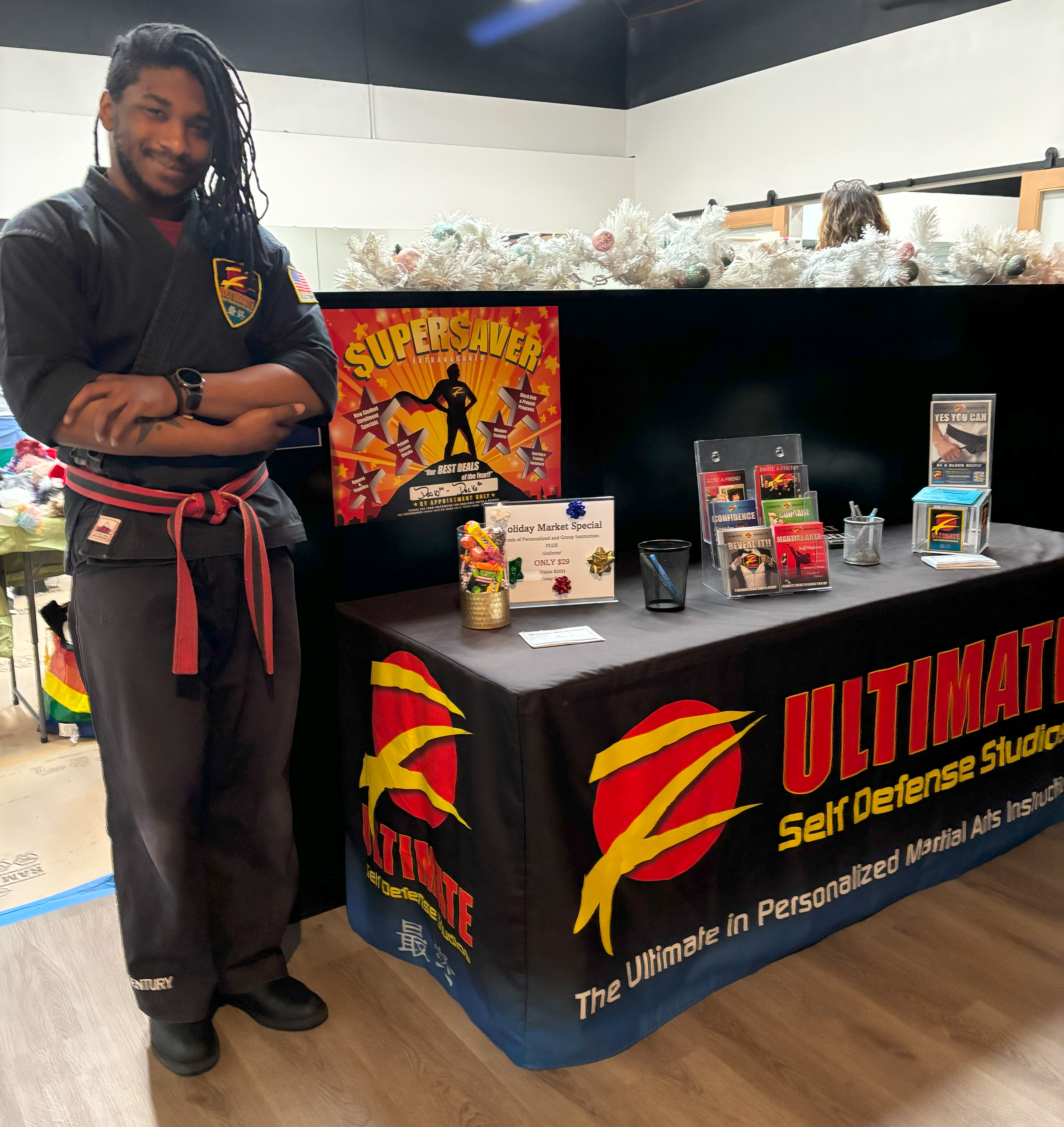 Person stands next to booth promoting our host's business z-ultimate self defense studio