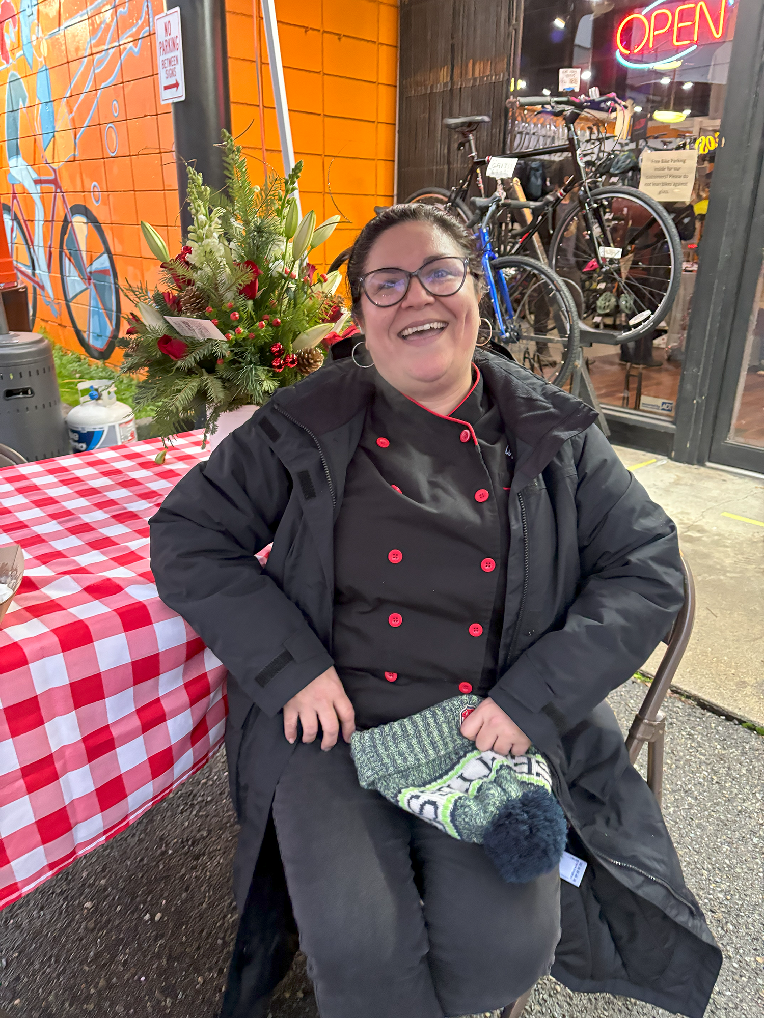 Person sits in front of holiday flowers at a red checkered table.