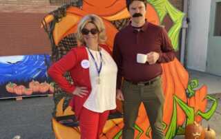 A couple dressed as characters from Parks and Rec pose with the pumpkin