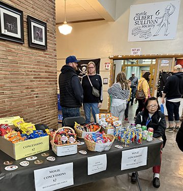 Lets all meet in the lobby! Lobby with concessions for sale and people preparing to watch a movie